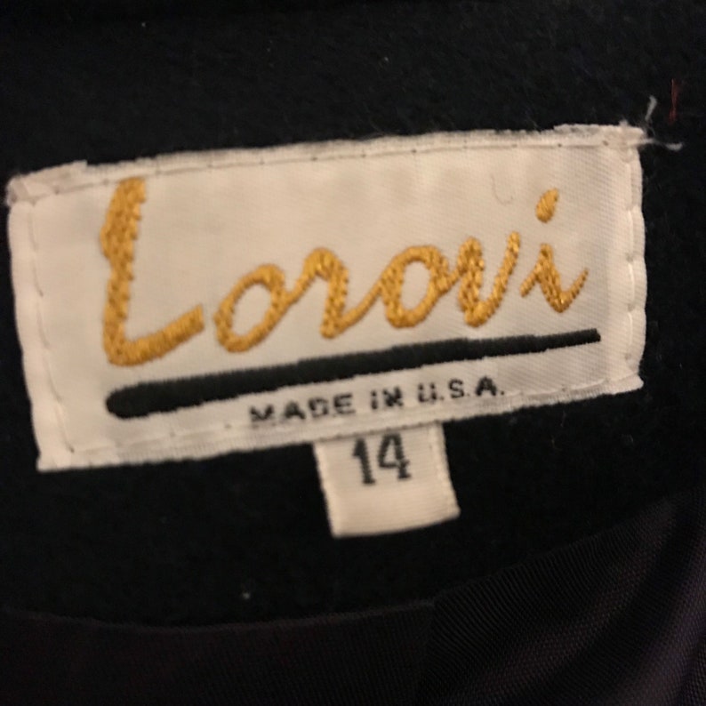 Pu&ograve; includere: Un'etichetta bianca con testo nero che recita "Lorori Made in U.S.A." e un'etichetta bianca pi&ugrave; piccola con il numero "14" su uno sfondo nero.