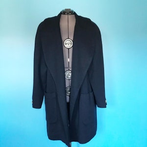 Pu&ograve; includere: Un lungo cappotto di lana blu navy con un ampio colletto e due tasche. Il cappotto ha una chiusura con un solo bottone e bottoni dorati.