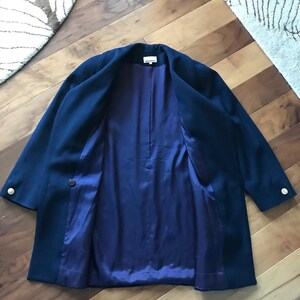 Pu&ograve; includere: Un blazer blu navy con fodera in raso blu scuro. Il blazer ha bottoni dorati e una chiusura con un solo bottone.