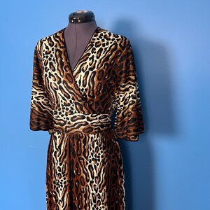 Puede incluir: Un vestido de envoltura de estampado de leopardo marr&oacute;n y blanco con cuello en V y mangas 3/4.