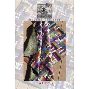 May include: A colorful quilt with a geometric pattern. The quilt is folded in half and is lying on a wooden surface. The quilt is made of various fabrics in shades of purple, green, red, and yellow. The quilt is titled "tatami" and is part of the "beyond the reef" collection.