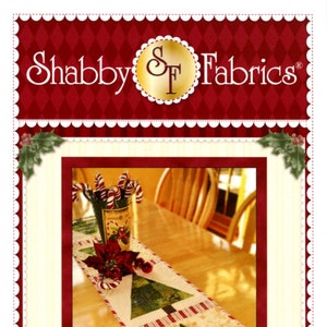 May include: A patchwork Christmas tree table runner with green, red, and white fabric. The runner is on a wooden table with a vase of candy canes and a poinsettia.