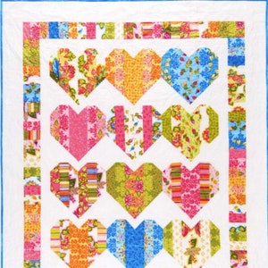 May include: A quilt with a white background and a patchwork design of colorful hearts. The hearts are made of different fabrics with floral and striped patterns in shades of pink, blue, green, orange, and yellow.