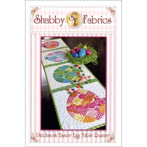 May include: A patchwork Easter egg table runner with four colorful egg designs. The runner is white with green trim and features a scattering of green and white jelly beans.