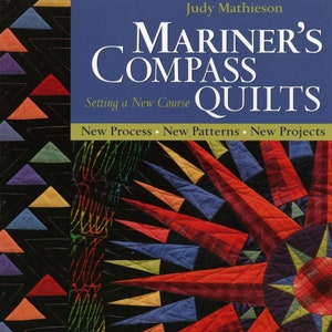 May include: A book cover with the title "Mariner's Compass Quilts: Setting a New Course" by Judy Mathieson. The cover features a colorful quilt with a starburst design in shades of red, blue, yellow, and orange.