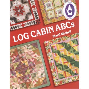 May include: Book cover with the title "Log Cabin ABCs" by Marti Michell. The cover features four colorful quilt blocks with a log cabin pattern.
