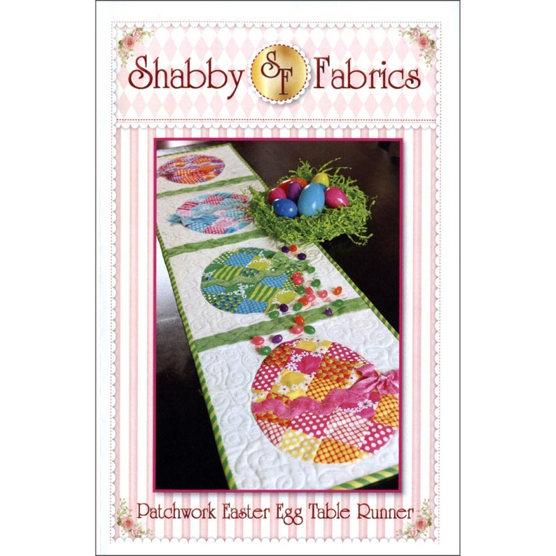 Puede incluir: Un camino de mesa de Pascua de patchwork con cuatro dise&ntilde;os de huevos coloridos. El camino de mesa es blanco con ribete verde y presenta una dispersi&oacute;n de gominolas verdes y blancas.