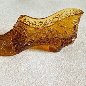 May include: A vintage amber glass shoe shaped trinket dish. The dish is decorated with a diamond pattern.