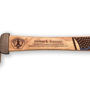 May include: A wooden sword with a round pommel and a wrapped handle. The blade features an American flag design with a blue line. Text includes a name, police unit, and division.