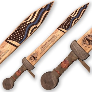 May include: Wooden sword featuring an American flag design with a blue line, and the text "JEFFERY R." and "ALBUQUERQUE POLICE". The handle is wrapped in leather and wood.