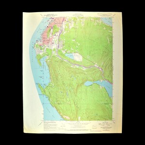 May include: A vintage topographic map of Bellingham, Washington, featuring detailed land contours, roads, and water bodies. The map uses a color scheme of green, blue, and pink, with text labels and grid lines.