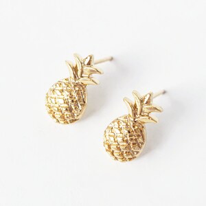 Könnte beinhalten: Ein Paar goldene Ananas-Ohrstecker. Die Ohrringe sind klein und zart und wären ein tolles Geschenk für jemanden, der Ananas liebt.
