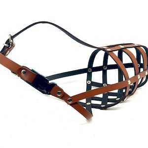 May include: A brown leather dog muzzle with a metal cage design and adjustable strap. The muzzle has a buckle closure and is designed to prevent biting.
