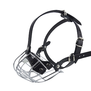 May include: A dog muzzle featuring a metal cage and black leather straps. The muzzle has a cage design at the front and adjustable leather straps with silver buckles for a secure fit. The leather is black.