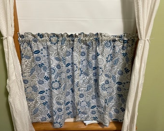 May include: A pair of gray and blue patterned valance curtains with a white sheer curtain on each side.