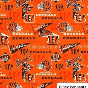 May include: Orange fabric with a repeating pattern of black and white Cincinnati Bengals logos, including the team's mascot, a tiger, and the words "Cincinnati Bengals". The fabric also features pennant flags with the words "Cincy Pennants".
