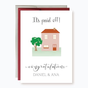 May include: A white card with a red envelope. The card has a pink house with a red roof and a green tree. The text on the card reads "It's paid off! Congratulations Daniel & Ana".