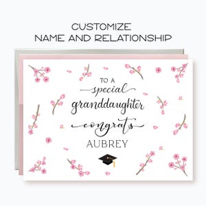 May include: A white card with pink cherry blossom flowers and the text "To a special granddaughter congrats Aubrey".