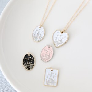 May include: Four gold necklaces with different pendant shapes featuring a white castle design. The pendants are a circle, a heart, a square, and a circle with a black background.
