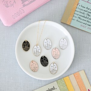 May include: A gold chain necklace with six different colored oval charms featuring a black and white outline of Cinderella's castle. The charms are displayed on a white plate. The text "Welcome to Disneyland" is visible on a ticket.