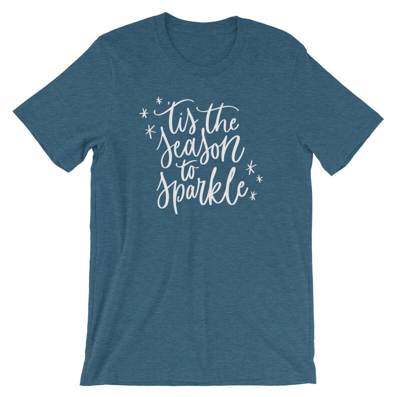May include: A teal blue t-shirt with the text "Tis the season to sparkle" in white lettering.