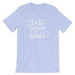 May include: Light blue t-shirt with the text "Tis the season to sparkle" in white lettering with snowflakes.