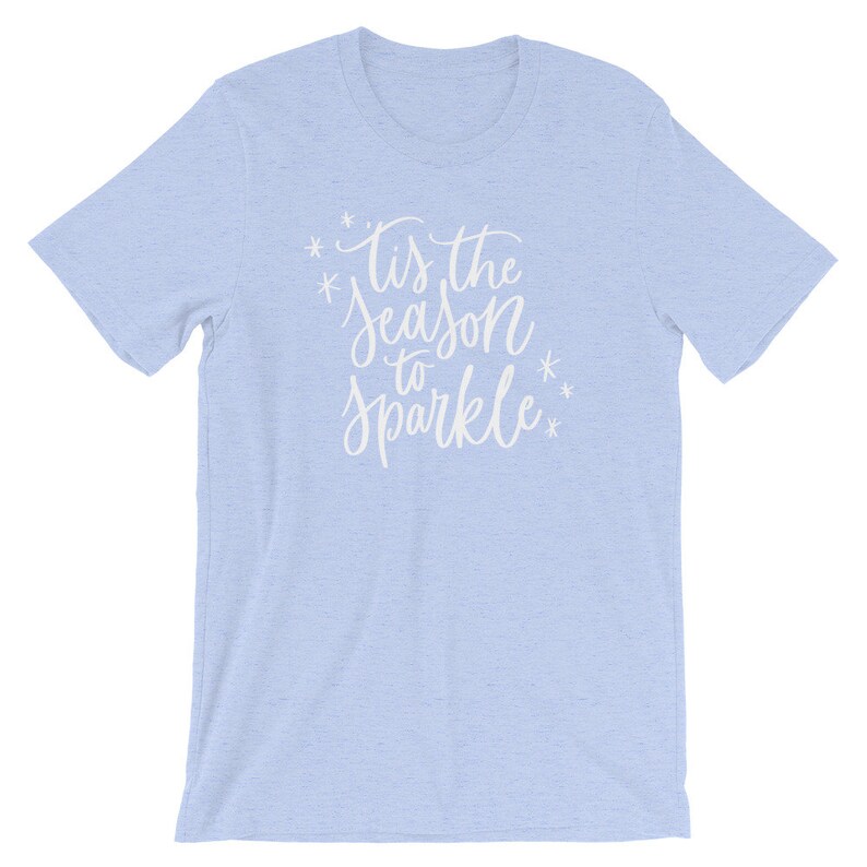 May include: Light blue t-shirt with the text "Tis the season to sparkle" in white lettering with snowflakes.