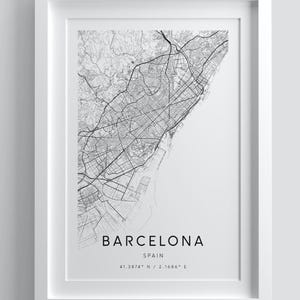 Könnte beinhalten: Ein gerahmter Schwarz-Weiß-Karten-Druck von Barcelona, Spanien, mit dem Layout und den Straßen der Stadt. Der Druck trägt die Aufschrift "Barcelona" und enthält die Koordinaten 41.3874° N / 2.1686° E. Der Rahmen ist weiß, und der Text "DESIGN 1 - MODERN" steht oben.