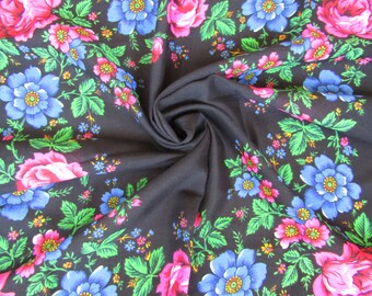 May include: Black fabric with a floral pattern featuring large pink and blue flowers, green leaves, and smaller colorful blossoms. The fabric is folded, creating a swirling effect.