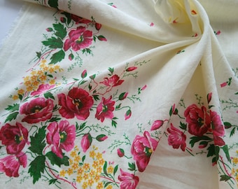 May include: Cream-colored fabric with a floral pattern featuring large, vibrant pink and red flowers, green leaves, and yellow accents. The fabric is draped, showing the texture and design. Ideal for home decor or crafting.