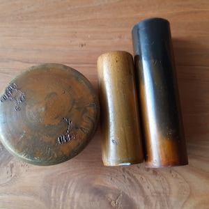 Puede incluir: Un conjunto de tres sellos de madera antiguos. Los sellos incluyen un sello redondo y plano con detalles tallados y dos sellos cilíndricos de diferentes tamaños y colores, que van del marrón claro al marrón oscuro.