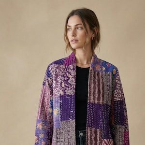 May include: A patchwork jacket in shades of purple, lavender, and pink. The jacket features a variety of patterned fabric squares, creating a unique and artistic design. The jacket has long sleeves and a collarless design.