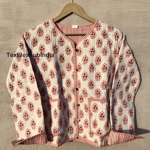 May include: White quilted jacket with a red and white striped trim. The jacket has a button closure and two pockets. The fabric features a floral print in shades of red and orange.
