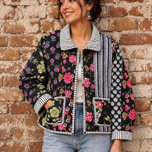 Peut inclure: Une veste matelassée à fond noir ornée de motifs floraux roses et verts vifs, agrémentée d'un panneau et d'un col à rayures verticales. Le vêtement comprend deux poches plaquées à l'avant, des manches longues à poignets rayés et une fermeture boutonnée.
