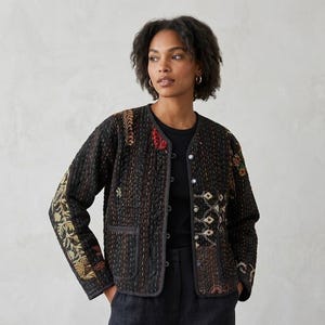 May include: A dark quilted jacket with detailed embroidery in red, gold, and green. The jacket has a round neckline, button closure, and two front pockets. The sleeves and front panels are decorated with floral and geometric patterns.