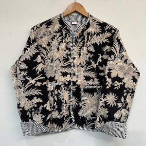 May include: A black quilted jacket with a floral print and a striped collar. The jacket has two pockets on the front.