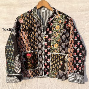 May include: Black quilted jacket with a floral print and a zipper closure. The jacket has a mandarin collar and two patch pockets.