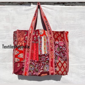 May include: A red patchwork tote bag with white and red striped handles. The bag is made of quilted fabric with a variety of floral and geometric patterns.