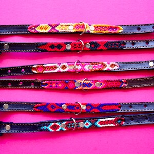 May include: Five colourful dog collars with leather straps and metal buckles. The collars feature a variety of woven patterns in red, blue, yellow, white and black.