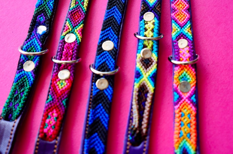 May include: Five colourful dog collars with different geometric patterns. The collars are made of woven fabric and have silver metal clasps.