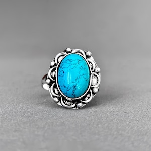 Op de afbeelding: Een zilveren ring met een turquoise ovale steen gezet in een decoratief filigraanontwerp.