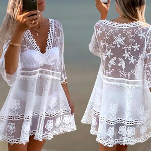 May include: White crochet beach cover-up with a V-neckline and floral embroidery. The cover-up has a loose fit and a flowy silhouette.