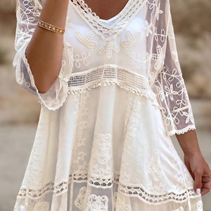 May include: White crochet dress with a lace overlay and a scalloped hem. The dress has a V-neckline and 3/4 sleeves.