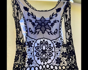 May include: Black crochet vest with a floral design. The vest is made of a sheer fabric and has a delicate lace trim.