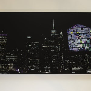 Puede incluir: Una ciudad nocturna con un edificio alto en el centro, iluminado con luces de colores. El edificio está rodeado de otros rascacielos, todos iluminados contra un cielo oscuro.