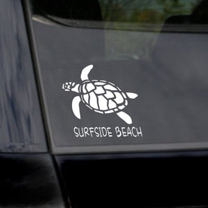 May include: White vinyl decal of a sea turtle with the text "Surfside Beach" on a black car.