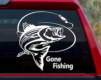 May include: White vinyl decal featuring a leaping fish with an open mouth, hook, and line, inside an oval. The words "Gone Fishing" are below the fish. The decal is on a red vehicle.