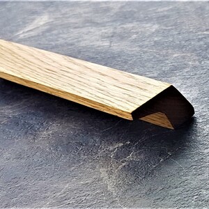 May include: A wooden cabinet pull with a dark brown finish and a triangular shape.
