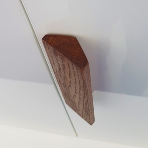 Può includere: Una maniglia per porta di armadio in legno marrone scuro a forma triangolare.