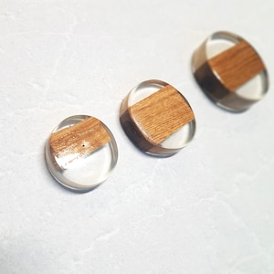 Könnte beinhalten: Drei runde Harz-Untersetzer mit Holzeinlage. Die Untersetzer sind klar mit einem Holzakzent in der Mitte.